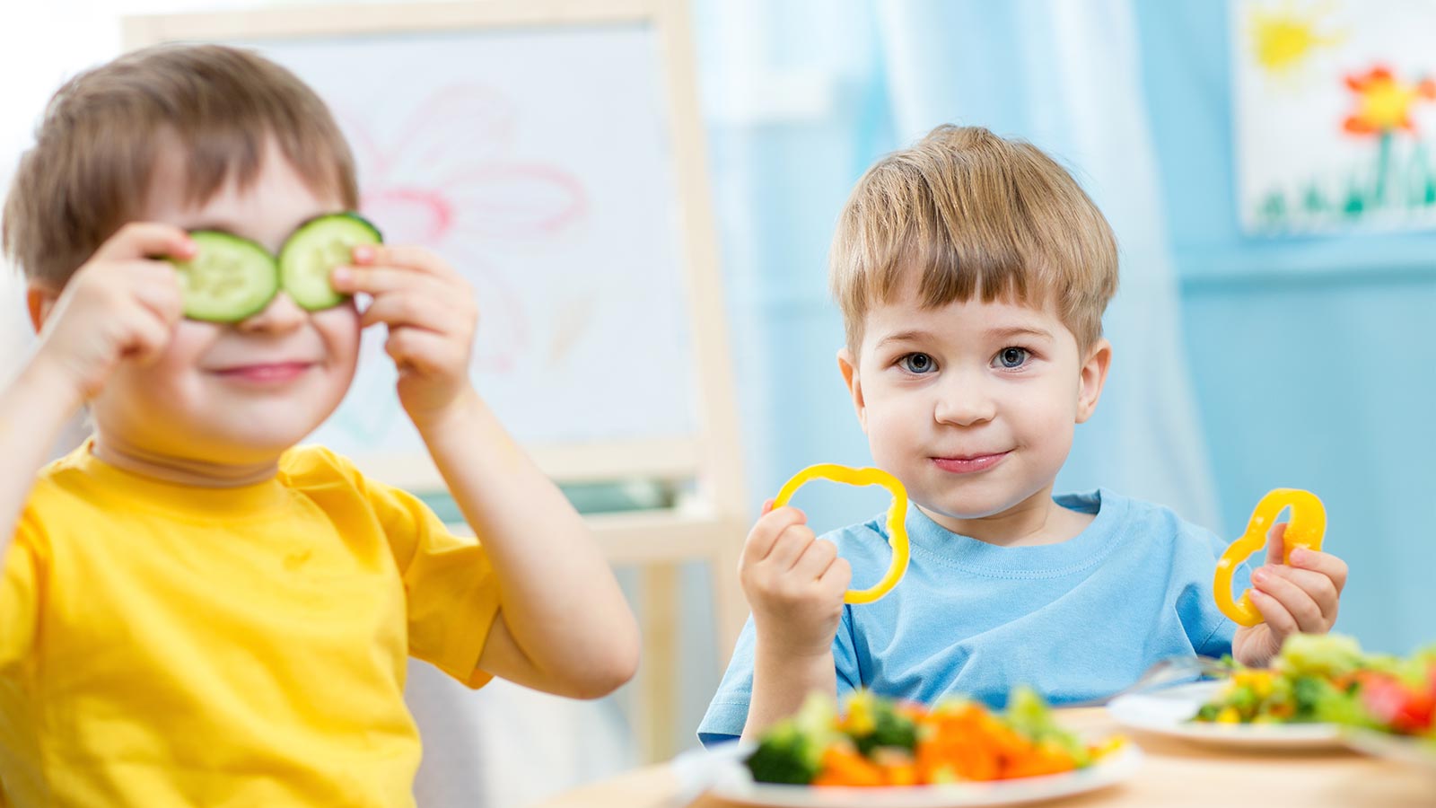 Due bambini giocano con le verdure presso la cucina dell'Hotel Livì a Livigno