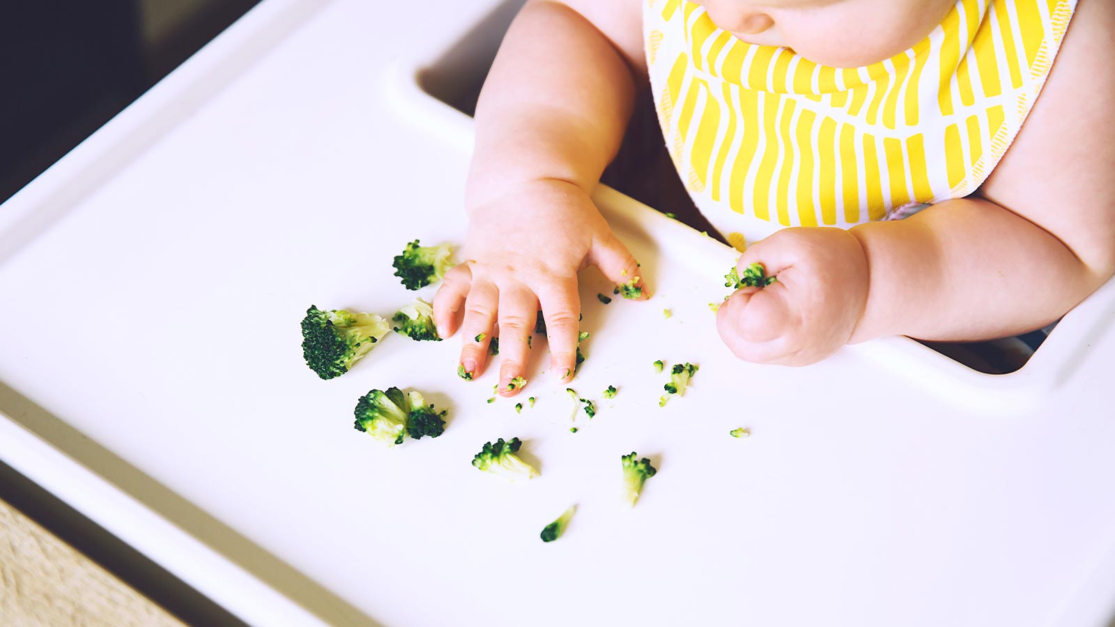Bambino sul seggiolone che mangia i broccoli presso l'Hotel Livì a Livigno